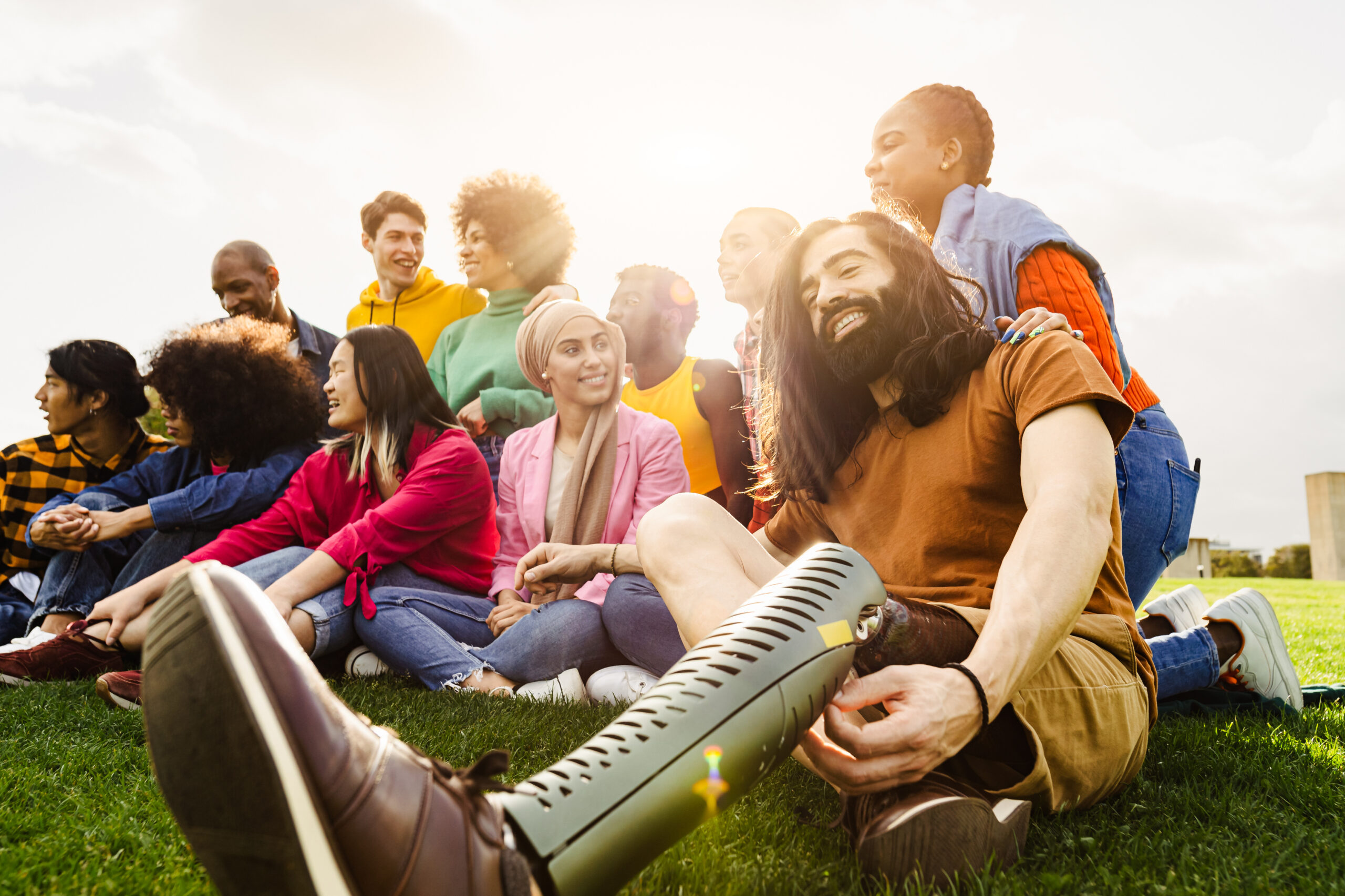 Multi ethnic group having fun in a public park - Amputee man hangs out with his friends outdoor - Friendship and diversity concept